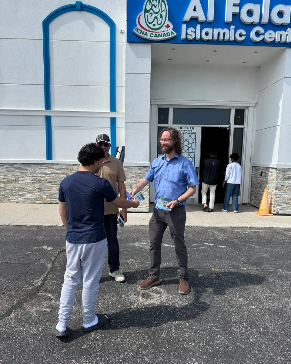 Matt shaking hands with a neighbour outside the Al Falah Islamic Centre