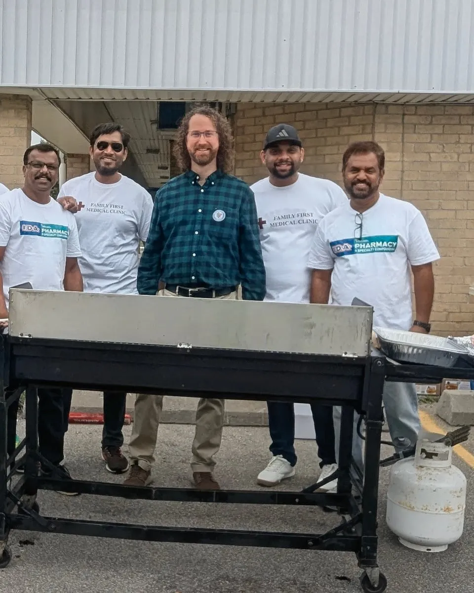 Matt and volunteers standing behind the grill at a community barbecue